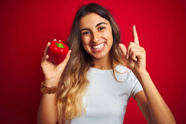 Ung Vacker Kvinna Som Håller Peppar Över Röd Isolerad Bakgrund — Stockfoto