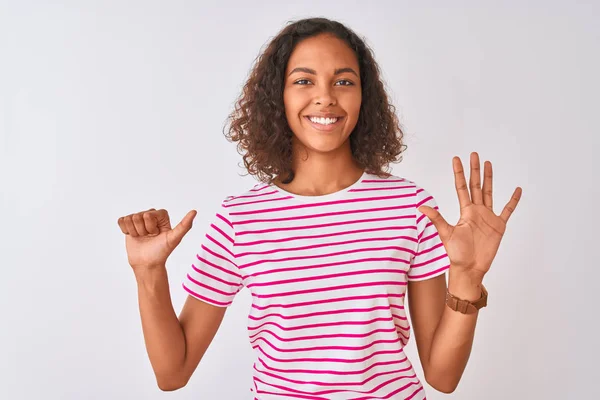 ピンクのストライプのTシャツを着た若いブラジル人女性が 自信を持って幸せな笑顔で指の数6を見せ 指差す白い背景の上に立って — ストック写真