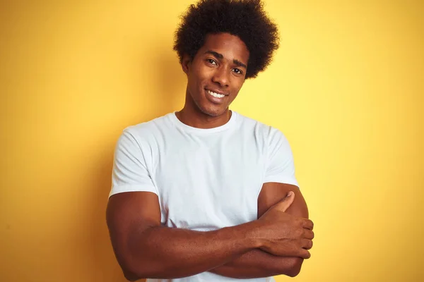 American man with afro hair wearing white t-shirt standing over isolated yellow background happy face smiling with crossed arms looking at the camera. Positive person.