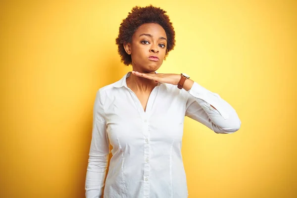 アフリカ系アメリカ人のビジネス女性がナイフのように手で喉を切断孤立黄色の背景に 激怒暴力で侵略を脅かす — ストック写真