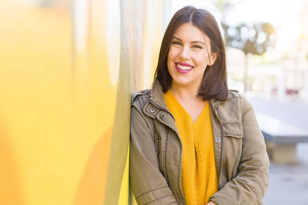 Mooie jonge vrouw glimlacht zelfverzekerd en vrolijk leunend op — Stockfoto