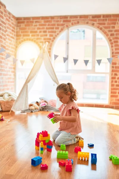 Schöne Blonde Kleinkind Mädchen Spielt Mit Plastikklötzen Einen Turm Kindergarten — Stockfoto