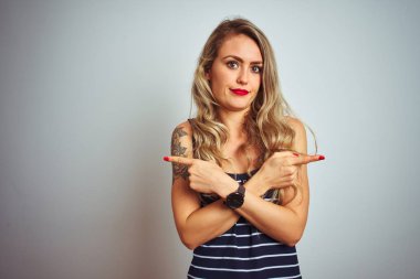 Çizgili tişört giyen genç ve güzel bir kadın beyaz izole edilmiş arka plan üzerinde duruyor. İki tarafı da parmaklarıyla işaret ediyor. Farklı yönler farklı.