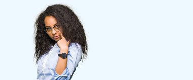 Gözlük giyen kıvırcık saçlı Genç güzel iş kızı sizi jest izlerken göz Işaret, şüpheli ifade