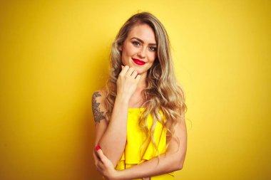 Sarı izole edilmiş arka planda duran tişört giyen genç saldırgan kadın çapraz kollar ve çeneyle gülümseyen kameraya kendinden emin bir şekilde bakıyor. Olumlu düşünüyorum..