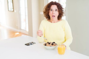 Sabah ları evde sağlıklı kahvaltı yiyen yaşlı kadın şaşkınlıkla şaşkın bir yüzle korkuiçinde, korku ve korkuyla heyecanlanırifade