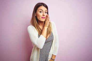Genç, güzel bir kadın pembe, izole edilmiş arka planda duruyor. Ağız üstünde el ele, gizli dedikodular, kötü niyetli konuşmalar.