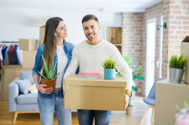 Güzel genç çift yeni bir ev, yeni bir dairede mutlu tutan karton kutular gülümseyen hareket