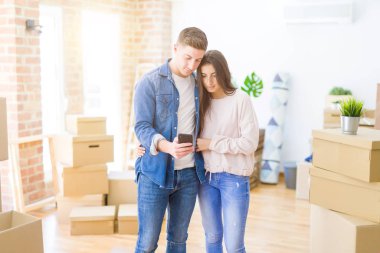 Güzel genç bir çift yeni bir eve taşınıyor. Akıllı telefon kullanıyorlar. Akıllı bir yüz ifadesi var.