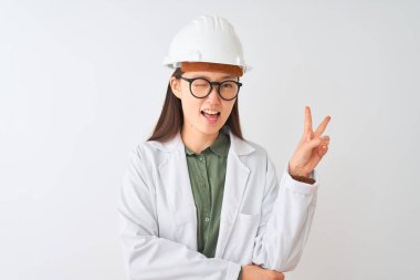 Genç Çinli mühendis kadın, izole edilmiş beyaz arka planda gözlük takıyor ve kameraya gülümsüyor. Zafer işareti yapıyor. İki numara..