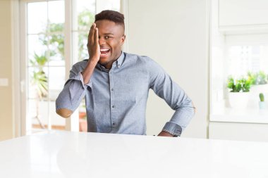 Yüzünde kendine güvenen bir gülümseme ve sürpriz duygu ile bir gözünü kaplayan beyaz masaüzerinde yakışıklı afro-amerikan adam.