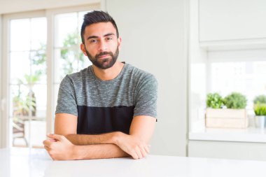 Yakışıklı, İspanyol tişörtlü ve yüzünde ciddi bir ifade olan bir adam. Basit ve doğal bir şekilde kameraya bakıyorsun..