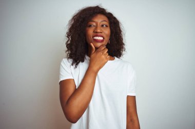 Genç Afro-Amerikalı kadın tişörtünü giyip izole edilmiş beyaz arka planda dikiliyor. Bir soru hakkında endişeleniyor, endişeli ve gergin.