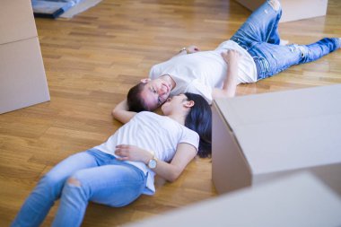 Genç güzel çift karton kutular etrafında yeni evde yatarken