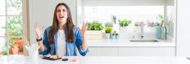 Geniş açılı bir bakış açısıyla, güzel bir kadının çılgın bir şekilde suşi yerken, bağırırken ve bağırırken saldırgan bir ifade ve kollar havada. Hayal kırıklığı konsepti.