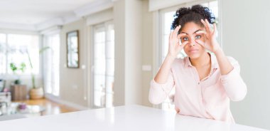 Afro saçlı güzel Afro-Amerikan kadının geniş açısı parmaklarıyla gözlerini açmaya çalışıyor, uykulu ve yorgun.