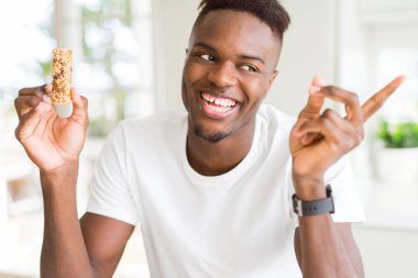 Afrika kökenli Amerikalı adam enerjik mısır gevrekleri yiyor. Elleri ve parmakları kenarda çok mutlu bir şekilde işaret ediyor.