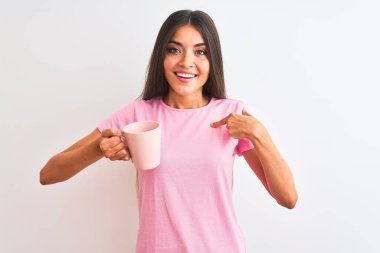 Genç ve güzel bir kadın pembe kahve içerken izole edilmiş beyaz arka planda durup kendini işaret eden sürpriz bir yüzle.