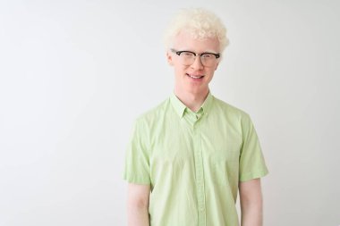 Yeşil tişörtlü ve gözlüklü genç albino sarışın adam izole edilmiş beyaz arka planda mutlu ve havalı bir gülümsemesi var. Şanslı kişi..