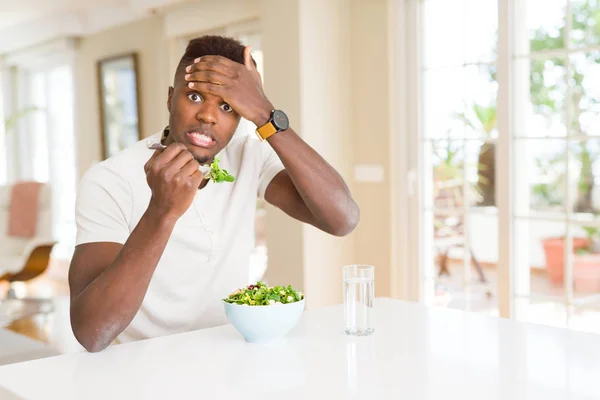 アフリカ系アメリカ人の男性は新鮮な健康的なサラダを食べる頭の上に手で強調し 恥と驚きの顔でショックを受け 怒りと不満 恐怖と過ちへの動揺 — ストック写真