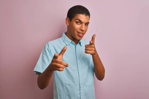 年轻英俊的阿拉伯男子穿着蓝色衬衫 站在孤立的粉色背景上 手指指向镜头 脸上洋溢着欢乐和滑稽的表情 好的能量和活力 — 图库照片