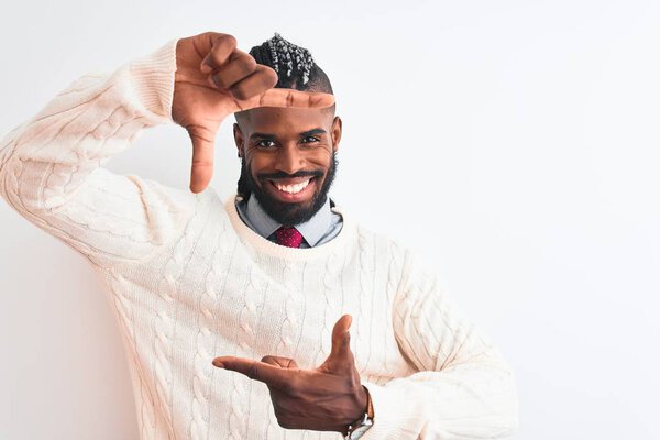 African american man with braids wearing white sweater over isolated white background smiling making frame with hands and fingers with happy face. Creativity and photography concept.