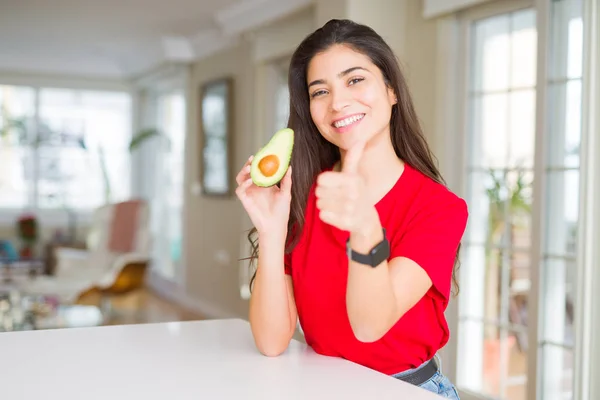 健康的なアボカドを食べる若い女性は Okサインをやって大きな笑顔で幸せ 指で親指アップ 優れた兆候 — ストック写真