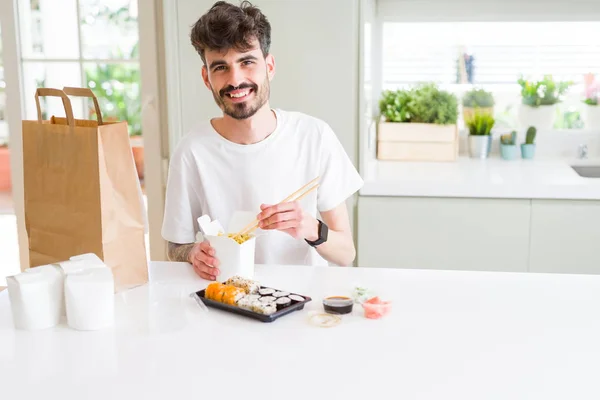 Young man eating sushi asian food and noodles using choopsticks