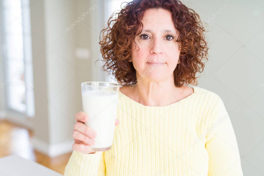 Senior woman drinking a glass of fresh milk with a confident expression on smart face thinking serious