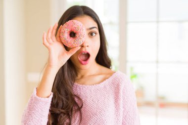 Güzel genç kadın ile göz üzerinde pembe donut ile bakıyor