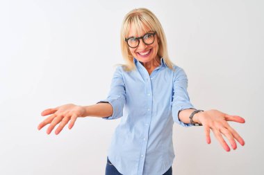 Zarif gömlek ve gözlük takan orta yaşlı bir iş kadını izole edilmiş beyaz arka planda gülümseyen neşeli bir şekilde yardım ve kabullenme eli uzatıyor..