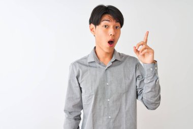 Soyutlanmış beyaz arka planda duran zarif gömlekli Çinli işadamı başarılı bir fikir işaret ediyor. Heyecanlı ve mutlu. Bir numara..