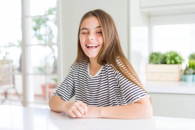 Çizgili tişört giyen güzel genç kız kameraya seksi bir ifadeyle bakıyor, neşeli ve mutlu bir yüzle..