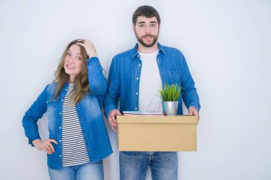 Karton kutu taşıyan genç bir çift beyaz izole edilmiş arka planda yeni bir eve taşınıyor. El ele, utanç ve şaşkınlık dolu, sinirli ve hayal kırıklığına uğramış bir halde. Hata için korku ve üzüntü.