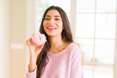 Genç güzel kadın pembe lezzetli donut gülümseyerek yemek 