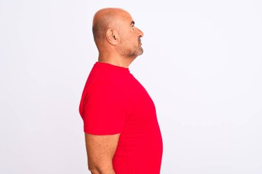 Orta yaşlı yakışıklı bir adam kırmızı günlük tişört giyiyor. İzole edilmiş beyaz arka plan üzerinde duruyor. Yan tarafa bakıyor..