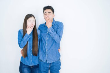 Beyaz, soyutlanmış arka planda yaşayan genç ve güzel Asyalı bir çift ağız kaplamaktan sıkılmış. Huzursuz ve uykulu..