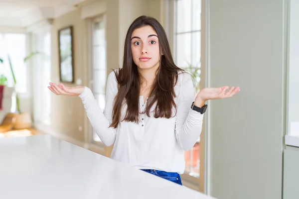 Mulher Bonita Sentada Mesa Branca Casa Sem Noção Expressão Confusa — Fotografia de Stock