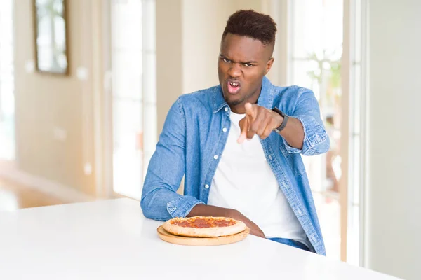 Africano Americano Comendo Pizza Pepperoni Casa Apontando Com Dedo Para — Fotografia de Stock