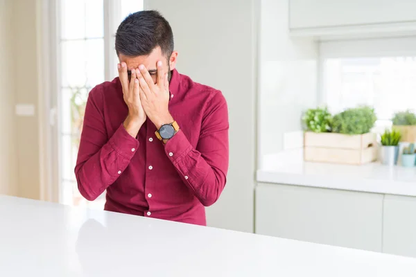 Handsome hispanic business man with sad expression covering face with hands while crying. Depression concept.