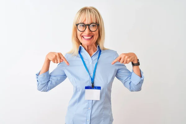 Middle age businesswoman wearing glasses and id card over isolated white background looking confident with smile on face, pointing oneself with fingers proud and happy.