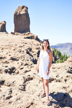 Genç ve güzel bir kadın dağ manzarasında yaz tatilinin tadını çıkarıyor. Gran Canaria 'daki Roque Nublo dağının tepesinde mutlu bir şekilde gülümsüyor.