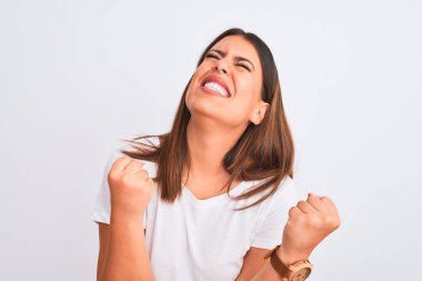 Güzel ve genç esmer bir kadının portresi izole edilmiş beyaz arka planda mutlu ve heyecanlı bir şekilde kollarını kaldırıp, gülümseyerek ve başarı için çığlık atarak kazanan bir jest yapıyor. Kutlama konsepti.