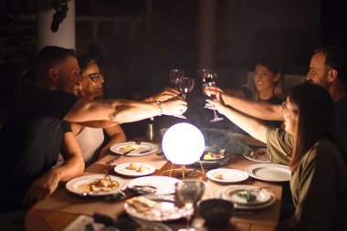 Güzel bir aile terasta bir bardak şarapla kadeh kaldırıyor.