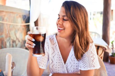 Genç ve güzel bir kadın restoranda oturmuş, yaz tatilinin tadını çıkarıyor.