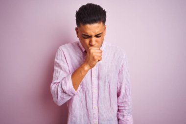 İzole edilmiş pembe arka plan üzerinde duran genç Brezilyalı adam kendini iyi hissetmiyor ve soğuk algınlığı veya bronşitin belirtisi olarak öksürüyor. Sağlık hizmetleri kavramı.