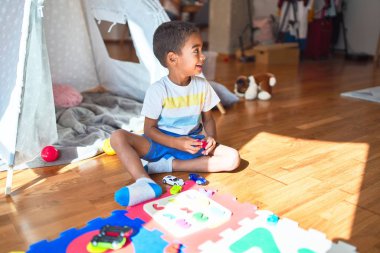 Güzel Afrikalı Amerikalı çocuk anaokulundaki rakamları kullanarak matematik oyunu oynuyor.