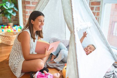 Anaokulunda Tip 'in içinde yerde yatan sarışın kıza güzel bir öğretmen kitabı okuyor.