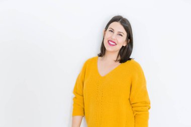 Güzel esmer genç kadın kendine güvenen ve neşeli rahat sarı kazak giyen izole beyaz arka plan üzerinde gülümseyen