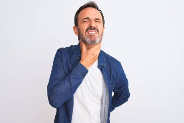 Orta yaşlı, mavi kot giyen yakışıklı bir adam izole edilmiş beyaz arka planda dikiliyor. Ağrılı boynuna dokunuyor. Grip için boğazı ağrıyor.